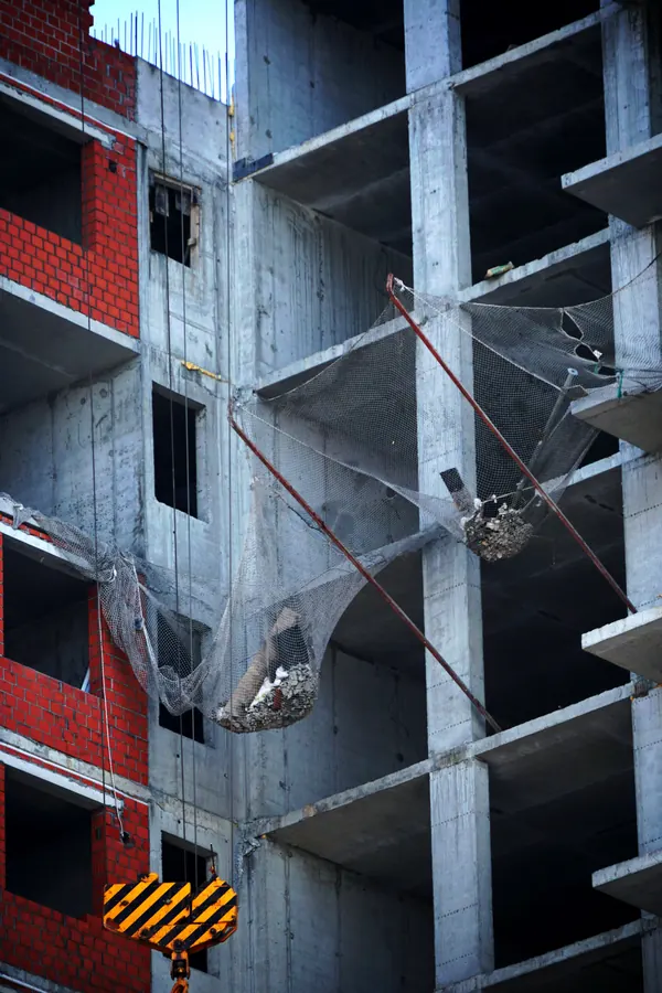 Concrete structural frame under construction with brick infill and lifting equipment