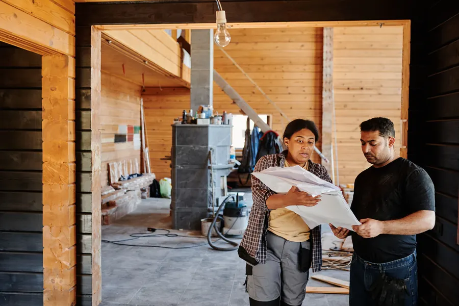 Two construction professionals reviewing building plans inside a structure