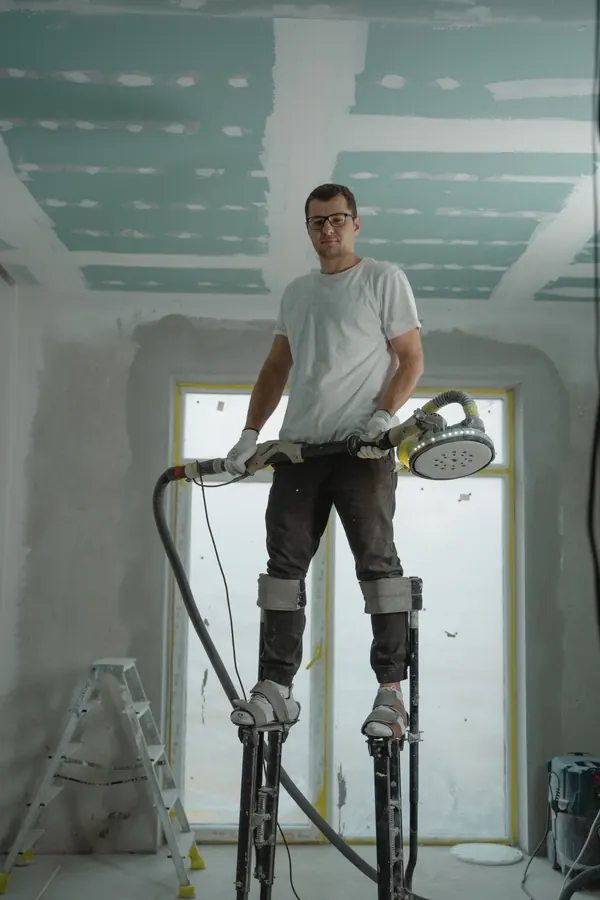 Construction worker on stilts preparing a ceiling inside a renovation site