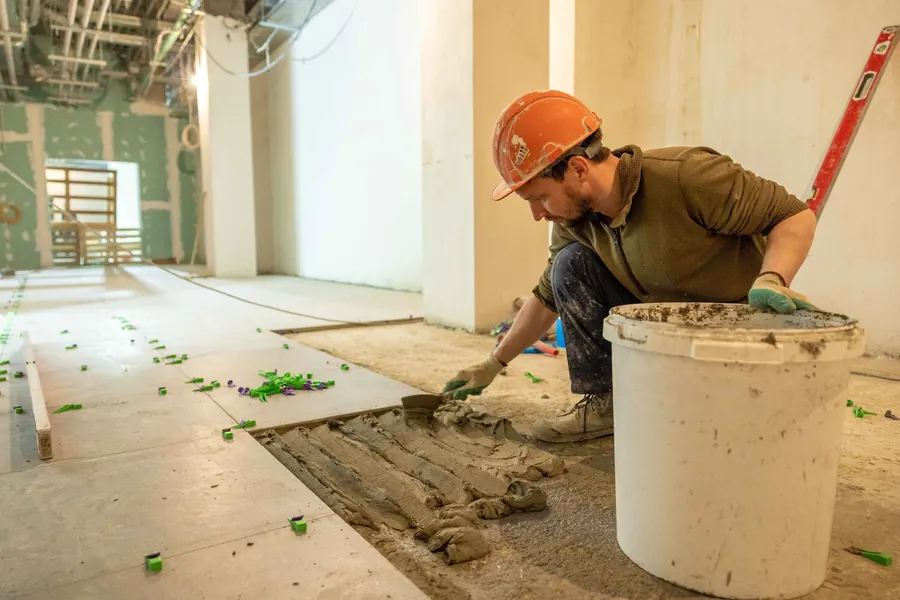 Construction worker installing floor tiles in an interior renovation